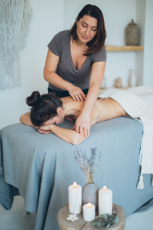 woman lying on bed while having a massage